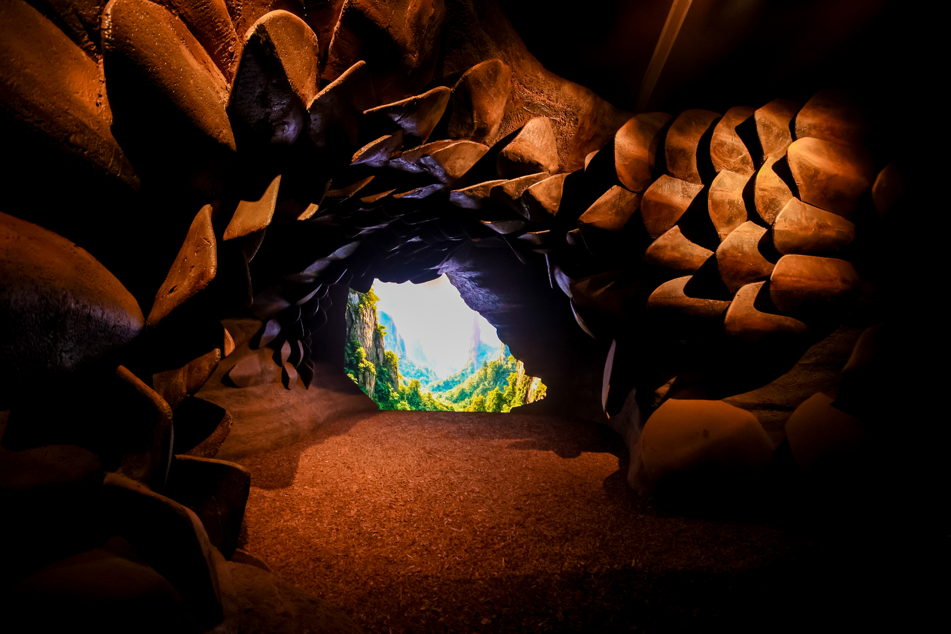 Cave-like exhibition chamber opening to a mountain landscape